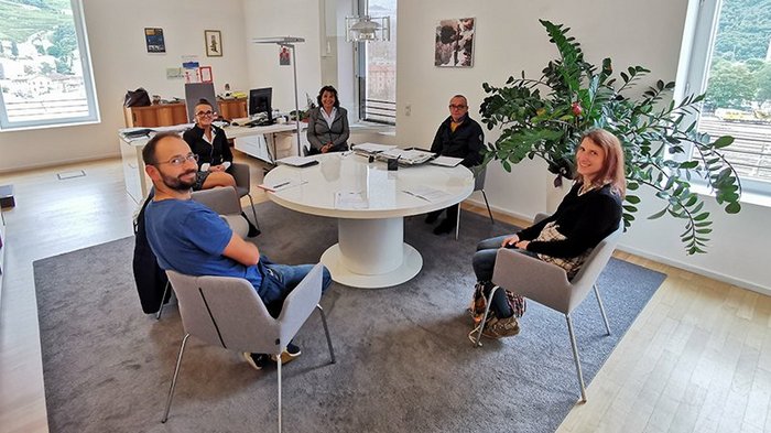 Ein "heißer" Ofen Fünf Personen sitzen um einen runden Tisch in einem Büro mit Fenster und Pflanzen