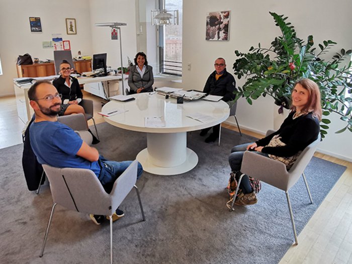 Ein "heißer" Ofen Fünf Personen sitzen um einen runden Tisch in einem Büro mit Fenster und Pflanzen