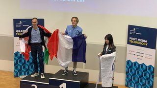 News Siegerpodium mit drei Personen, die Flaggen nach einer Grafiktechnologie-Meisterschaft halten.