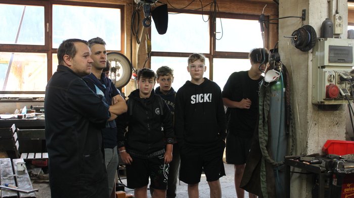 Esplorare nuovi saperi: il mondo delle professioni pratiche Gruppo di giovani e un uomo in un'officina con attrezzature meccaniche