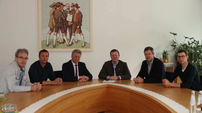 “Il regolamento dell'UE sulla deforestazione mette a rischio la gestione sostenibile delle foreste”. Sei uomini seduti intorno a un tavolo di legno rotondo in una sala riunioni con un quadro alla parete