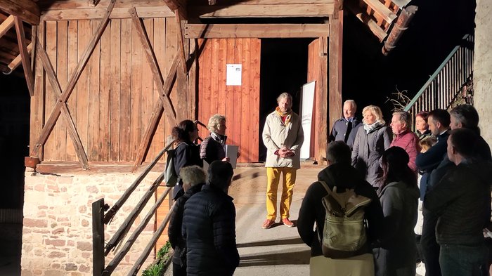 Neue Wege für Südtirol: Plattform Land setzt weiterhin auf nachhaltige Dorfentwicklung Gruppe von Menschen hört einer Person bei Nacht vor einem Holzgebäude zu