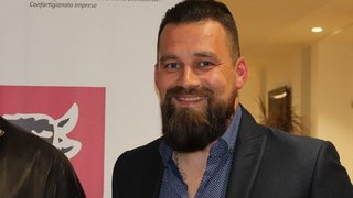 News Mann mit Bart lächelt vor Wirtschaftsbanner lvhapa