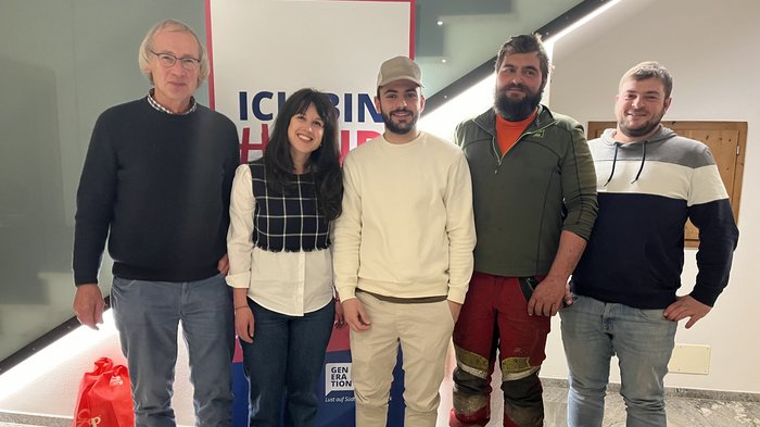 Neue Impulse für das Handwerk Fünf lächelnde Personen stehen vor einem Plakat mit Schrift im Gebäude