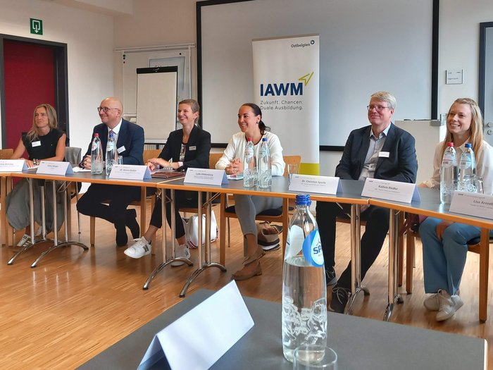 Europäisches Kammertreffen Menschen sitzen an einem Tisch bei einer Besprechung vor IAWM-Banner