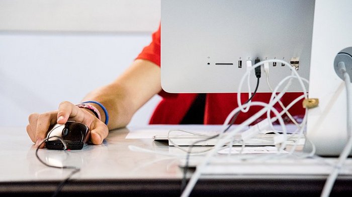 Zugang zu größeren Aufträgen durch Zusammenschlüsse Hand am Computermaus neben einem Monitor auf einem Schreibtisch