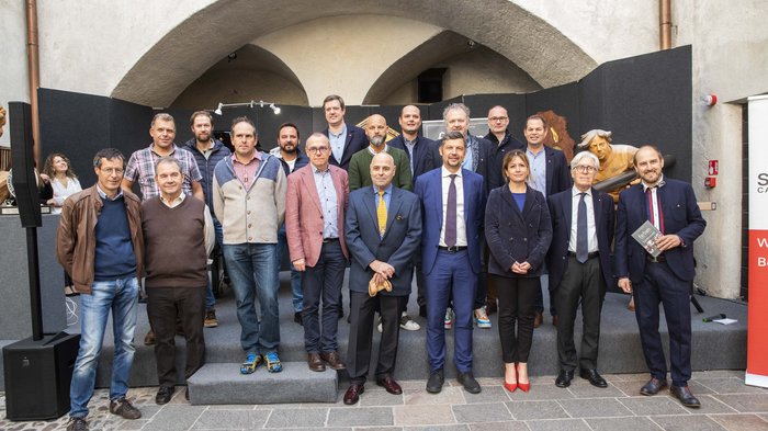© Alan Bianchi Gruppenfoto von 18 Personen vor einem historischen Gebäudebogen