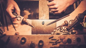 Home Gioielliere esamina una gemma blu con lente d'ingrandimento su banco da lavoro