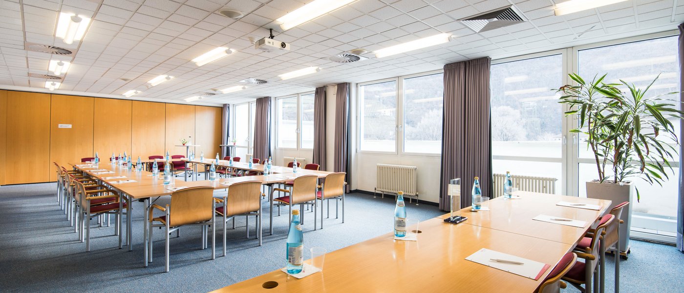 Affitto aule seminari Sala conferenze con tavoli, sedie, bottiglie d'acqua e blocchi per appunti