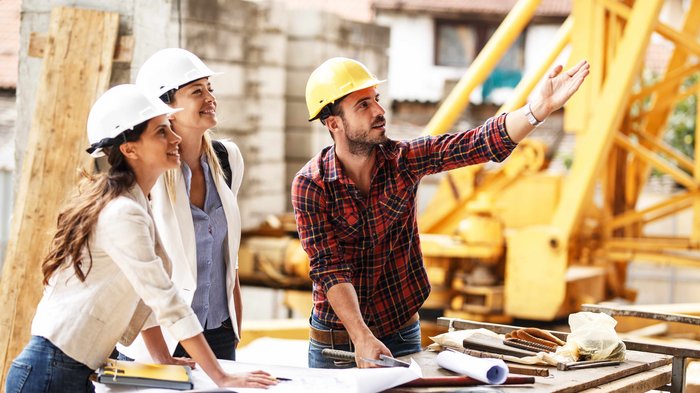 Presa di posizione sul sondaggio IPL: sostegno sociale sul posto di lavoro Ingegneri con caschi di sicurezza discutono progetti su un cantiere