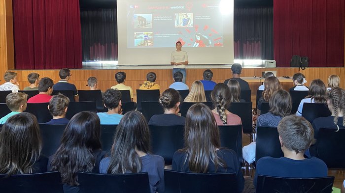 lvh und HGJ starten zum Schulbeginn wieder die Berufsinformationskampagne Lehrerin hält Vortrag vor Schülern in Aula über Handwerk und Frauen