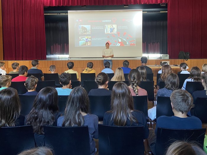 lvh und HGJ starten zum Schulbeginn wieder die Berufsinformationskampagne Lehrerin hält Vortrag vor Schülern in Aula über Handwerk und Frauen