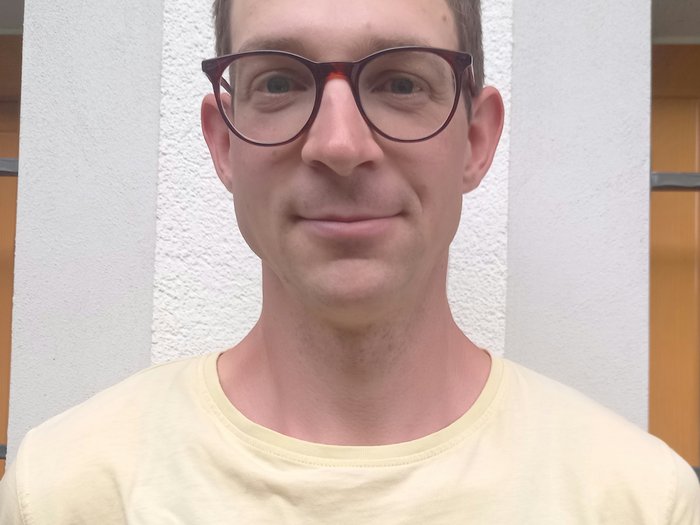 Confronto sulle sfide e sulle strategie future del settore forestale Ritratto di uomo con occhiali e maglietta gialla davanti a muro bianco