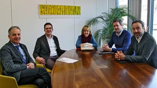 News Fünf Personen sitzen um einen Holztisch in einem Besprechungsraum