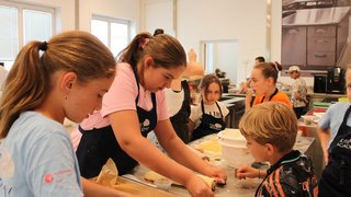 News Kinder rollen Teig und bereiten Gebäck in einer Küche vor