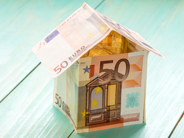 Der Superbonus 110%: Eine einmalige Gelegenheit für Privatpersonen und Betriebe Haus aus 50-Euro-Geldscheinen auf blauem Holzhintergrund