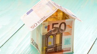 News Haus aus 50-Euro-Geldscheinen auf blauem Holzhintergrund