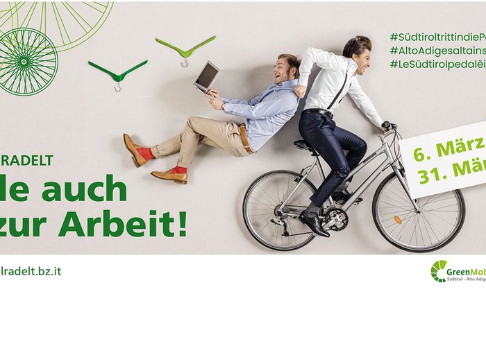 L'Alto Adige pedala. Pedala anche tu al lavoro! Due uomini, uno in bicicletta e l'altro seduto sul portapacchi, ridendo