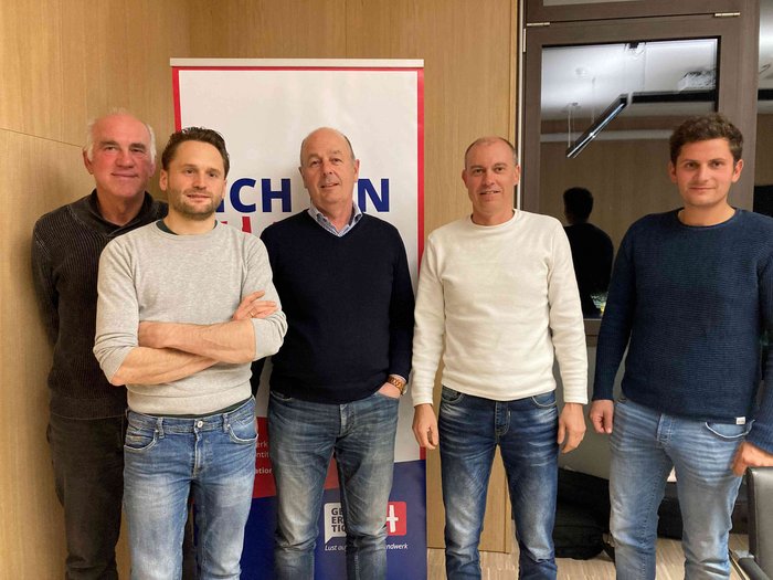 „Handwerker/innen sind Problemlöser“ Fünf Männer stehen vor einem Banner in einem Raum