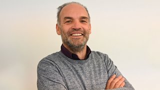 News Uomo sorridente con maglione grigio su sfondo bianco