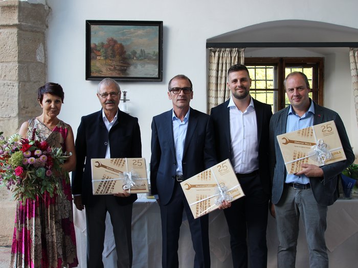 © SAG/Doris Mur Fünf Personen, drei mit Geschenkboxen zum 25-jährigen Jubiläum, eine Frau mit Blumenstrauß