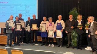 News Personen erhalten Auszeichnungen und Urkunden auf einer Bühne während einer Veranstaltung