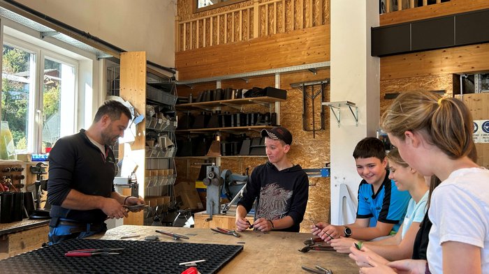 Entdeckungsreise in Berufe des Handwerks und Gastgewerbes an der Mittelschule St. Martin in Passeier Lehrer erklärt Werkzeugtechnik einer Gruppe Jugendlicher in Werkstatt
