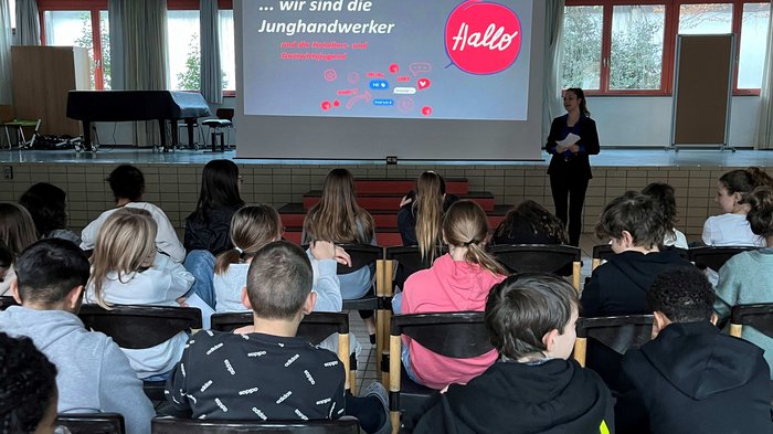„Mit unseren Ausbildungen ist vieles möglich!“ Schüler schauen einer Präsentation der Junghandwerker in einem Klassenzimmer zu