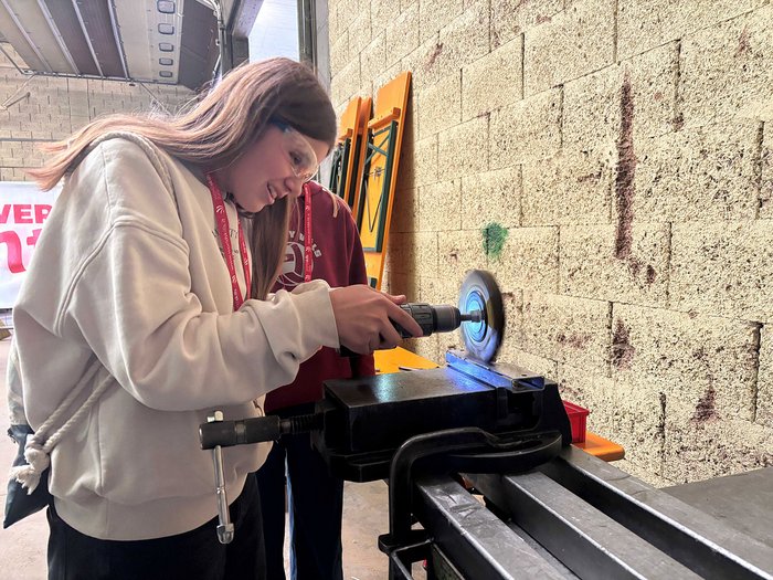 Handwerk hautnah: SkillsDay begeistert im Eggental Junge Frau benutzt Winkelschleifer mit Schutzbrille in Werkstatt