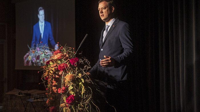 Tag des Handwerks - Jugend als Schlüssel für unsere Zukunft Mann hält eine Rede an einem mit Blumen geschmückten Rednerpult