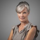 Doris Freydt Ritratto di donna sorridente con capelli grigi su sfondo grigio