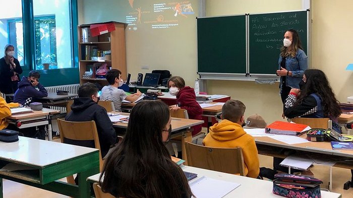 Die bunte Welt der Gastronomie und des Handwerks entdecken Schüler und Lehrerin im Klassenzimmer mit Masken während des Unterrichts