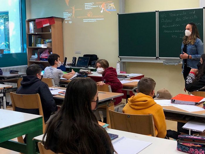 Die bunte Welt der Gastronomie und des Handwerks entdecken Schüler und Lehrerin im Klassenzimmer mit Masken während des Unterrichts