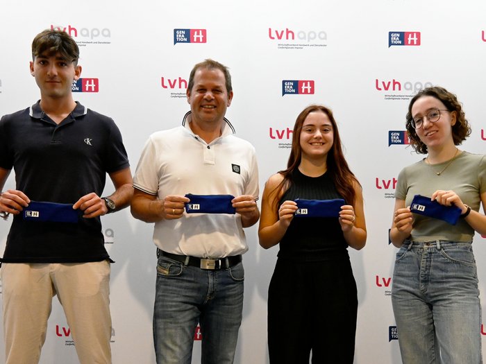 Berufsschüler/innen für das Handwerk begeistern Vier Personen halten blaue Etuis vor einer lvhapa und Generation H Wand