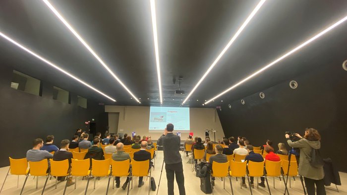 Il futuro è qui: il techParcour Persone sedute su sedie gialle assistono a una presentazione in sala conferenze moderna