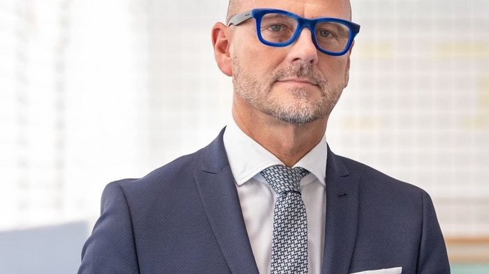 Appalti pubblici: la suddivisione in lotti tutela l’economia locale Uomo d'affari con completo blu e occhiali guarda verso la fotocamera