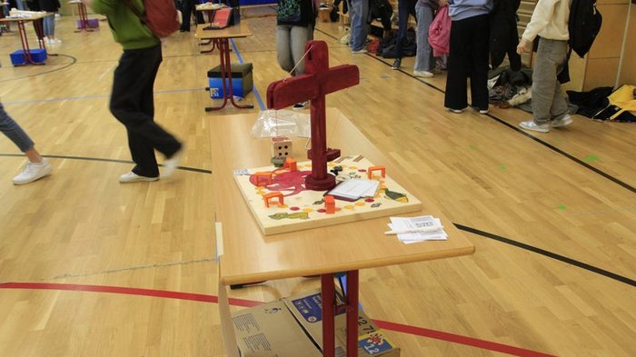 Kreative Spielideen: Preisverleihung für "Clever gebaut" Modell eines kleinen Krans auf einem Tisch in einer Turnhalle mit Schülerinnen und Schülern