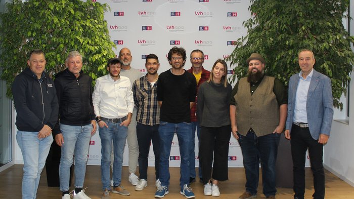 Jahresversammlung der Orthopädieschuhmacher/innen Gruppenfoto von zehn Menschen vor einer Wand mit lvh-apa-Logo in einem Büro