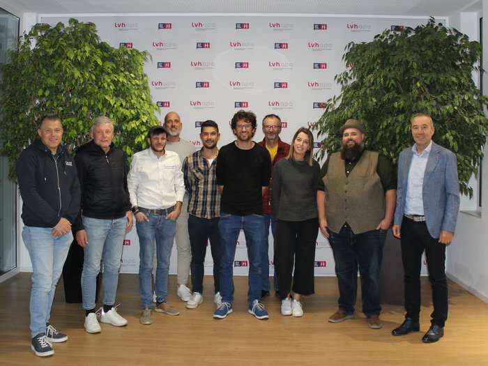 Jahresversammlung der Orthopädieschuhmacher/innen Gruppenfoto von zehn Menschen vor einer Wand mit lvh-apa-Logo in einem Büro