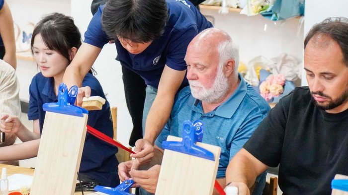 Führungswechsel Menschen arbeiten in einem Workshop mit Holzplatten und blauen Klemmen
