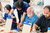 Menschen arbeiten in einem Workshop mit Holzplatten und blauen Klemmen