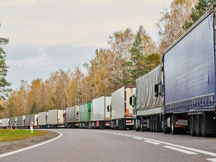 © Dmitry Kalinovsky/Shutterstock.com LKW stehen in einer langen Schlange auf einer Landstraße im Herbst