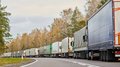 Divieto di transito notturno in Tirolo: una scelta ingiustificata Camion fermi in una lunga fila su una strada di campagna in autunno