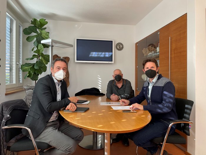 Appalti pubblici: numerose opportunità Tre uomini con mascherine in una riunione a un tavolo in ufficio