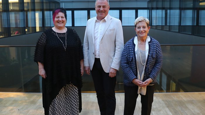 Neuer Obermeister des Südtiroler Meisterbundes Drei lächelnde Personen in einem modernen Gebäude mit Glasdach