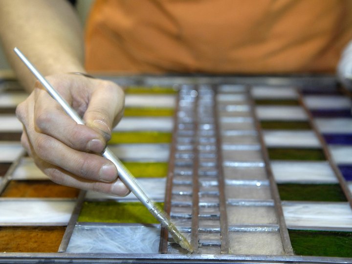 Vetrai Mano dipinge finestra in vetro con pennello e pezzi di vetro colorati