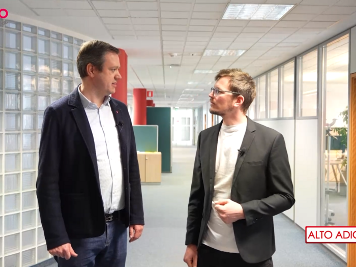 “Mondo artigiano”: la realtà delle piccole imprese va in onda Due uomini che parlano in un corridoio di ufficio moderno