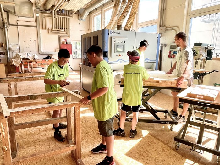 © lvh.apa Jugendliche und ein Erwachsener arbeiten an einer Holzwerkstatt mit Maschinen