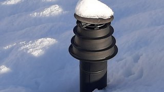 News Schwarzes Lüftungsrohr mit Schneekappe im Schnee