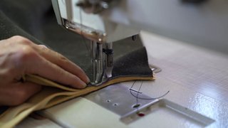 News Hand führt Leder durch eine Nähmaschine beim Nähen